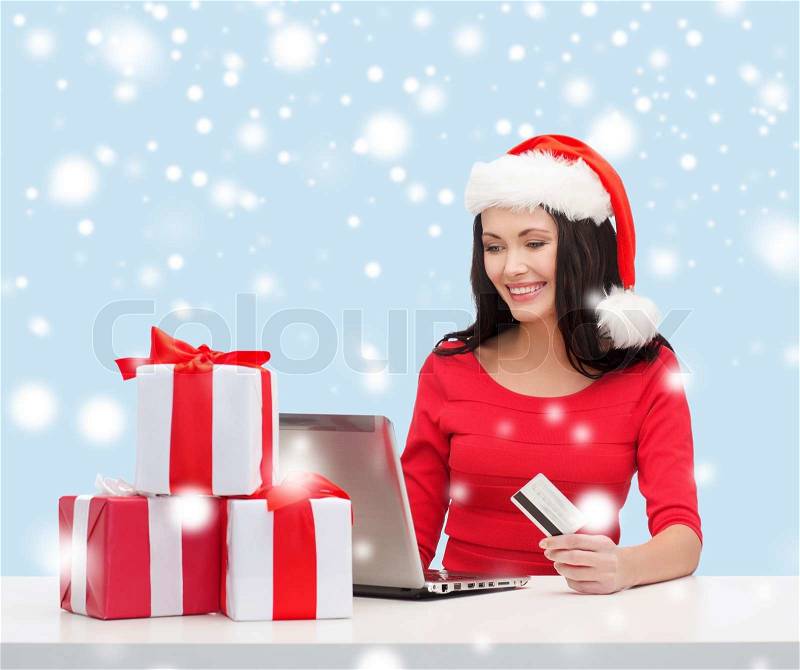 Christmas, x-mas, online shopping concept - woman in santa helper hat with gift boxes, laptop computer and credit card, stock photo