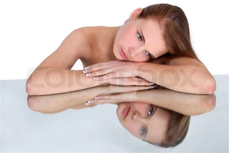 Woman resting head on reflective surface, stock photo