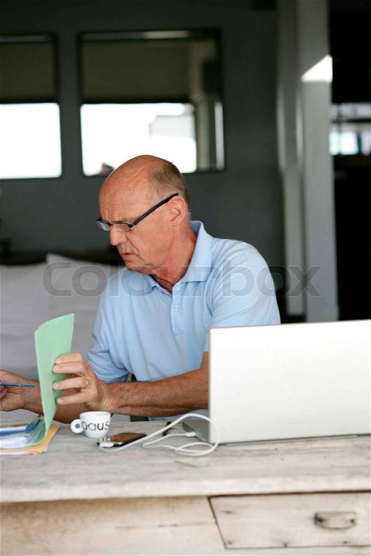 Senior man trying to sort hiss house bills out, stock photo
