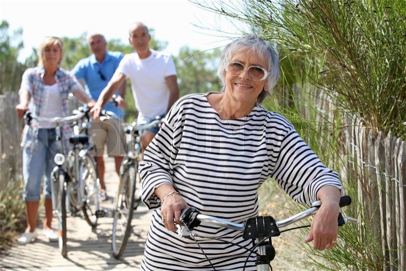 Middle-aged people on bike ride at the beach, stock photo