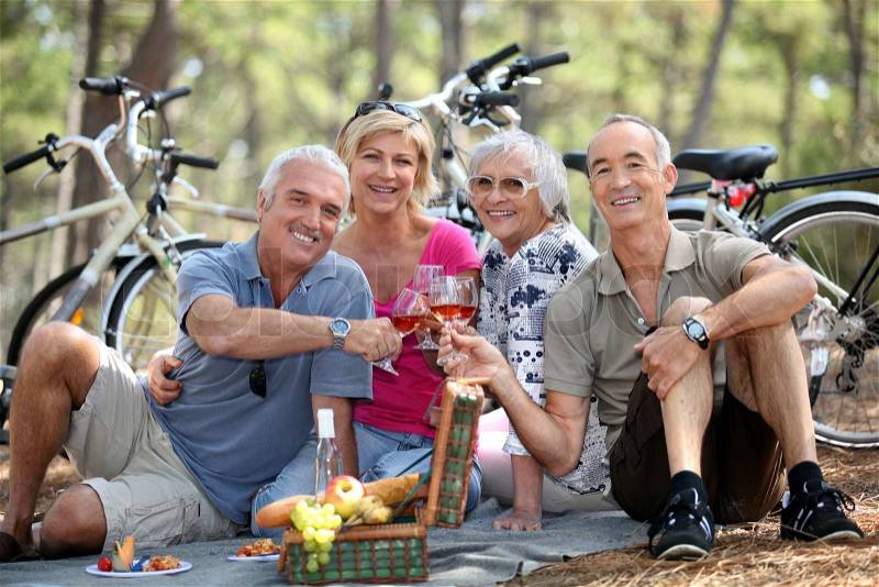 Two older couples enjoying a picnic in the woods, stock photo
