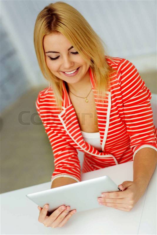 Young happy woman looking at tablet computer display, stock photo