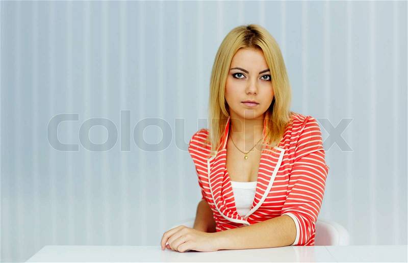 Young serious woman sitting at the table in office, stock photo