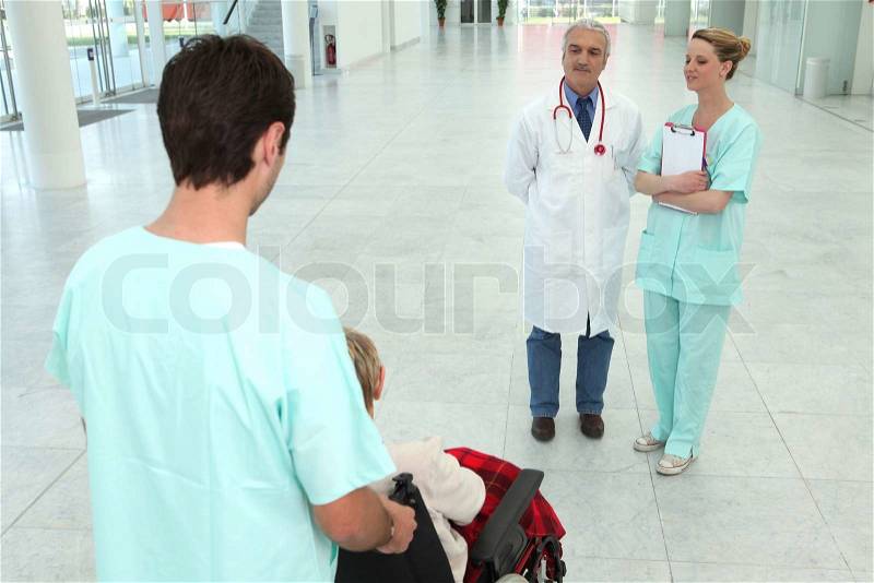 Hospital worker taking care of senior patient in a wheelchair, stock photo