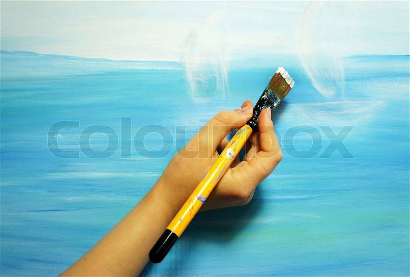 Detail of painter hand holding paintbrush a painting picture , stock photo