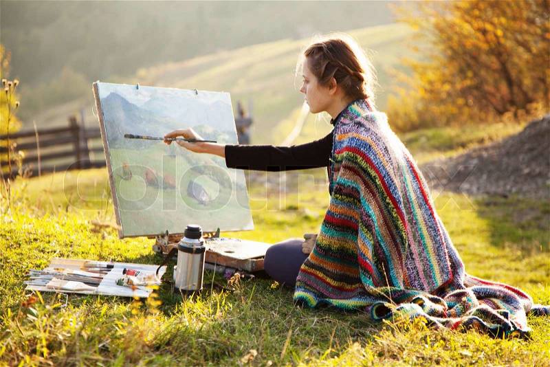 Young artist painting an autumn landscape, stock photo