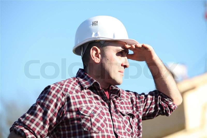 Tradesman shielding his eyes from the sunlight, stock photo