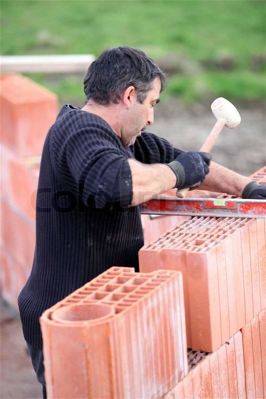Adjusting wall with wooden mallet, stock photo