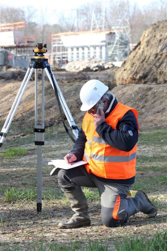 A land surveyor writing in his notebook while talking on the phone, stock photo