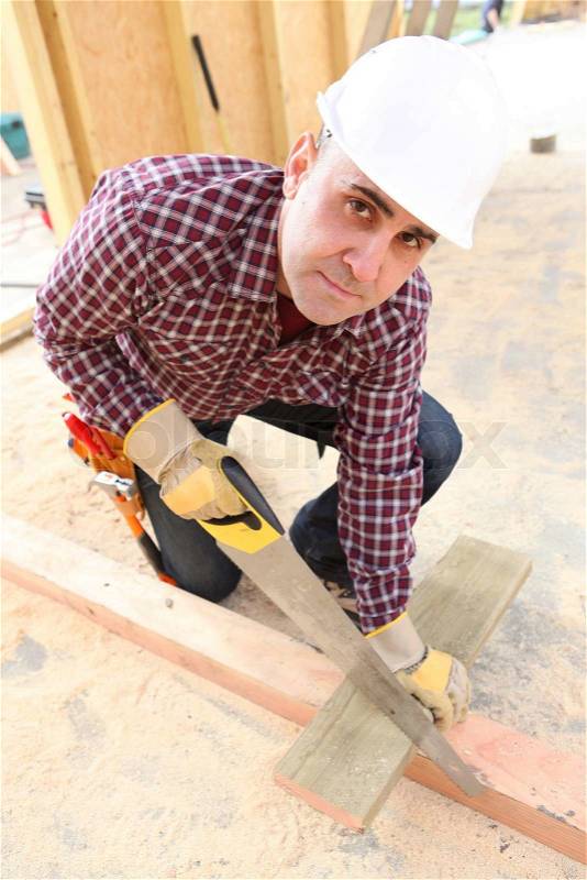 Builder sawing wood, stock photo