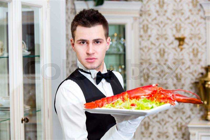 Waiter with lobster on a plate in a restaurant, stock photo