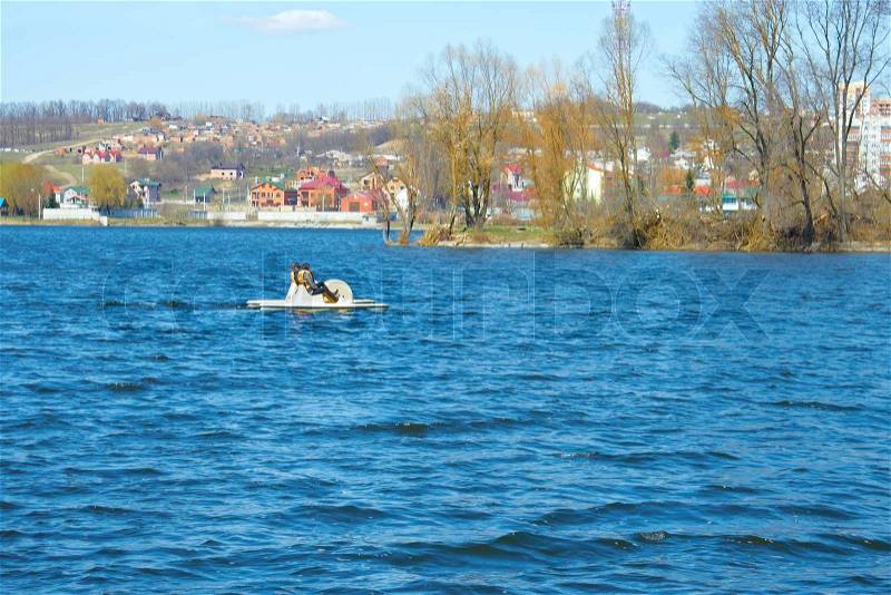 Two women walking on water bikes at the city reservoir an early spring in lovely sunny weather. Khmelnytsky, Ukraine, stock photo