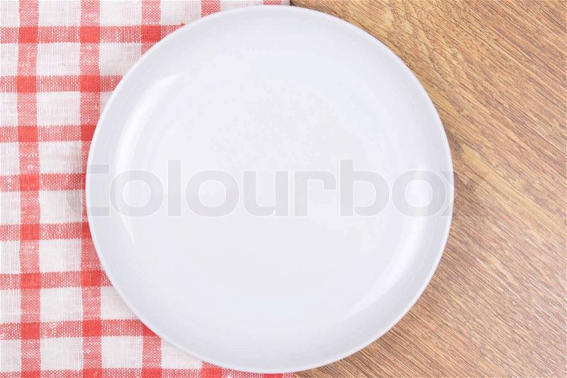 White empty plate on the wooden table with checkered tablecloth, stock photo