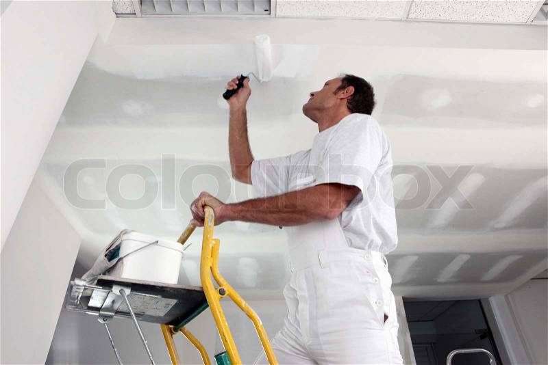 Tradesman painting a ceiling, stock photo