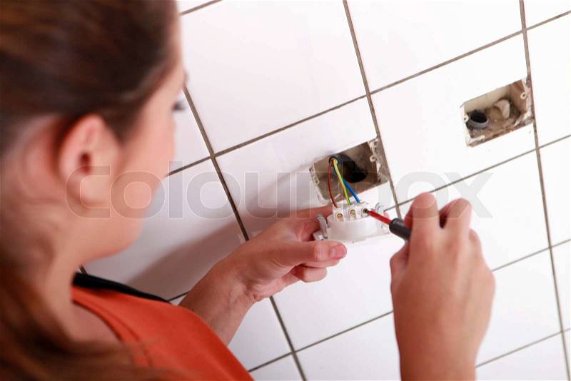 Woman electrician installing electrical outlet, stock photo