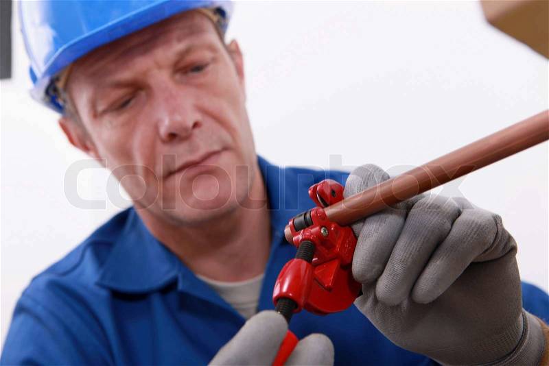 Plumber cutting a copper pipe with a pipe cutter, stock photo