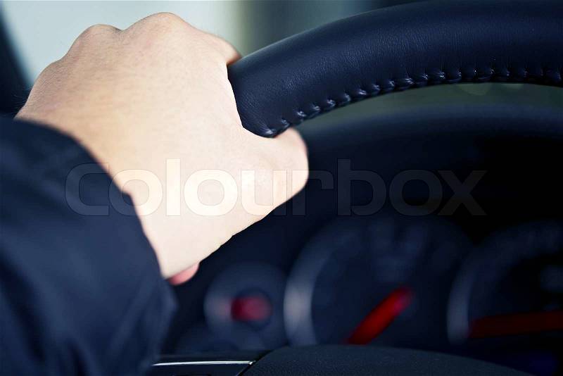 Men Left Hand on Car Steering Wheel. Driving Theme. Transportation Photo Collection, stock photo