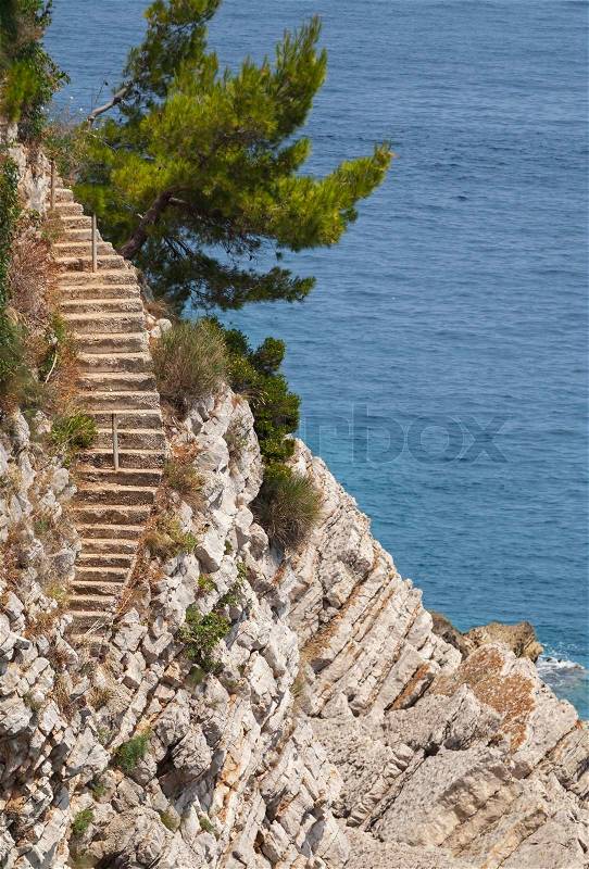 Old stone stairs goes down on the rock to the sea water, stock photo