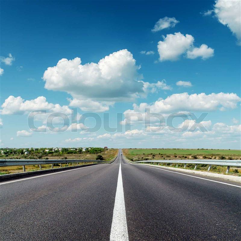 Asphalt road to horizon under cloudy sky, stock photo