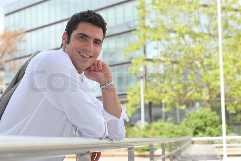 Businessman leaning on a rail in the sunshine, stock photo