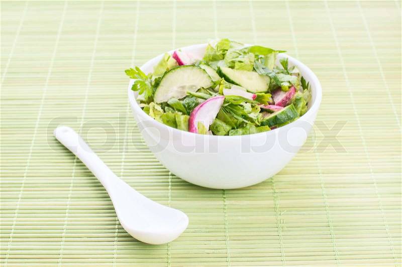 Chopped salad with goat cheese on a green background, stock photo