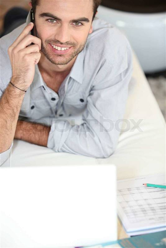 Man on bed telephoning, stock photo