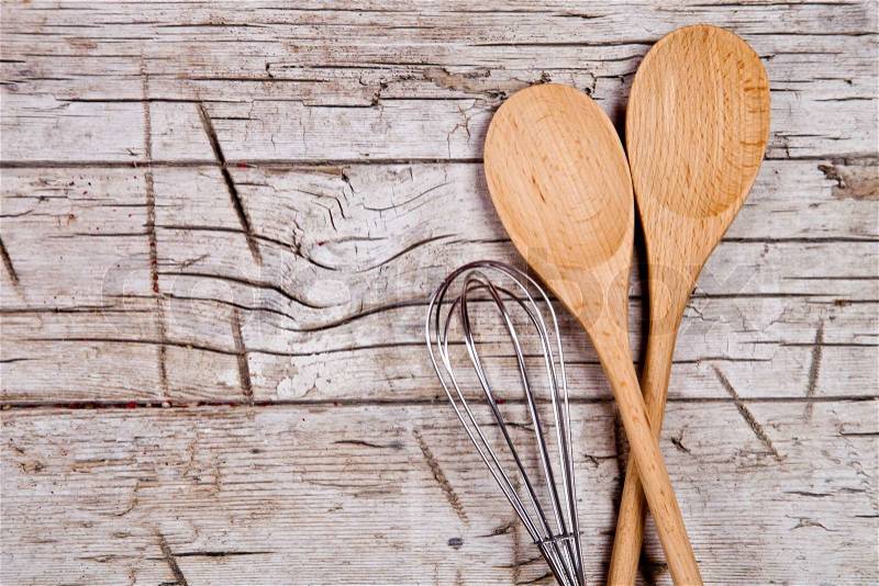 Spoons and wire whisk on rustic wooden background, stock photo