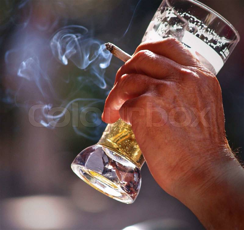 An old man sitting at the table in outdoor pub Drinking beer and smoking, stock photo
