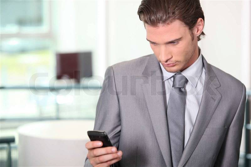 Male executive checking messages on cellphone, stock photo
