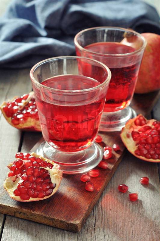 Ripe pomegranate fruit and glass of juice on wooden background, stock photo
