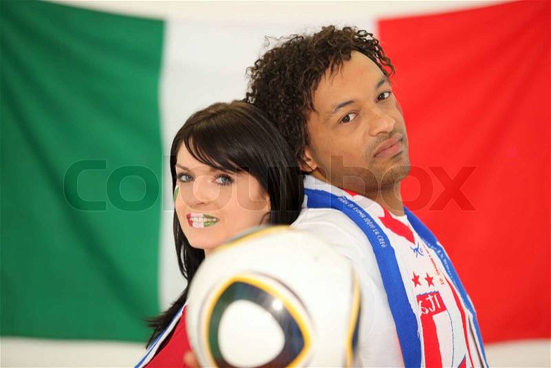 Couple of Italian soccer fans stood back to back, stock photo