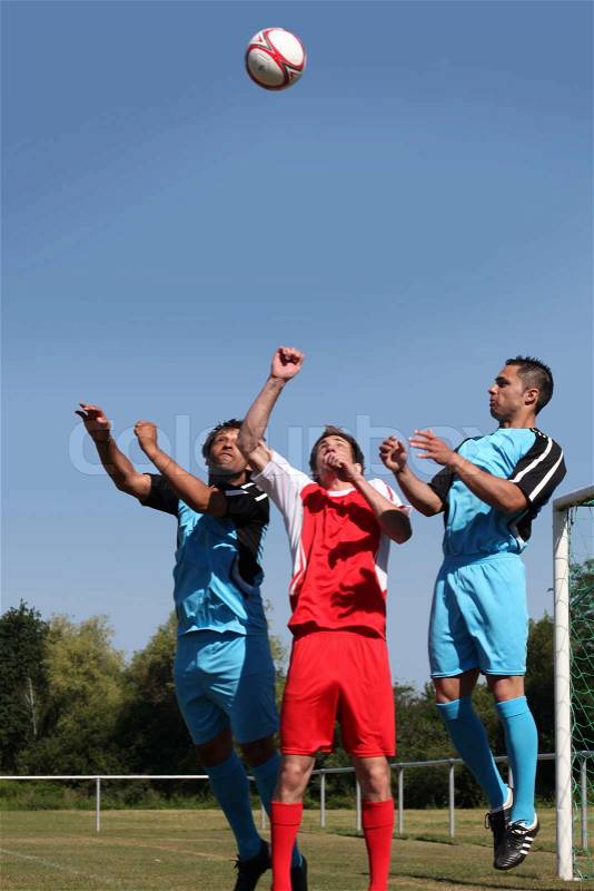 Footballers jumping for ball, stock photo