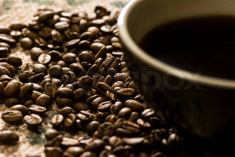 Bllack cup of coffee next to coffee beans on coffee sack, stock photo