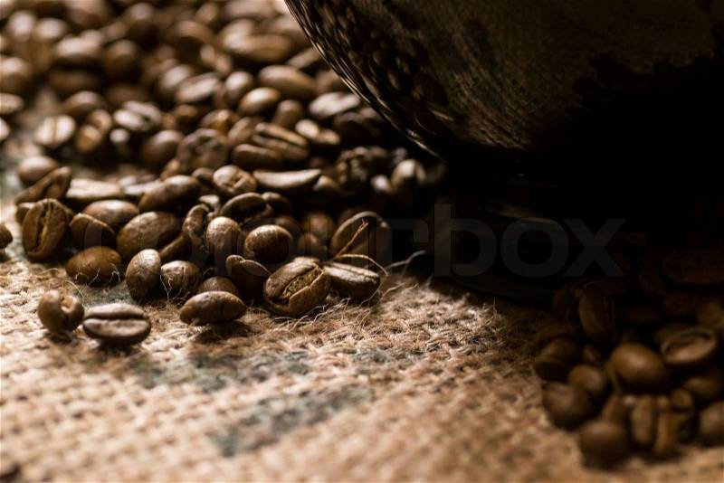 Black cup of on a coffee sack with roasted beans around, stock photo