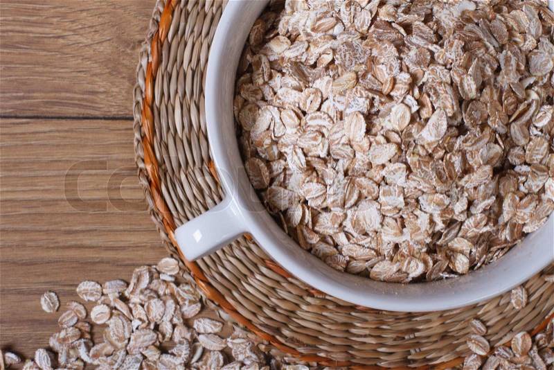 Oat flakes in a bowl and scattered on the table. View from above. close-up, stock photo