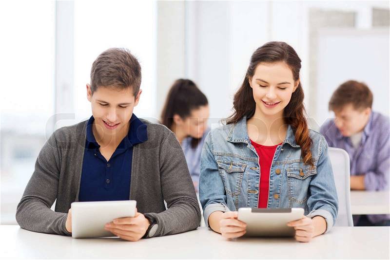 Education, technology and internet - two smiling students looking at tablet pc in lecture at school, stock photo