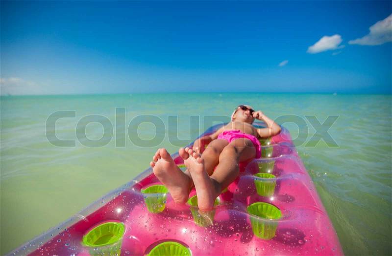 Little cute girl on pink air-bed sunbathe in Caribbean sea, stock photo