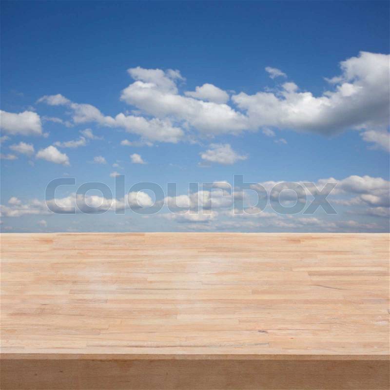 Empty wooden table in a garden on blue sky background, stock photo