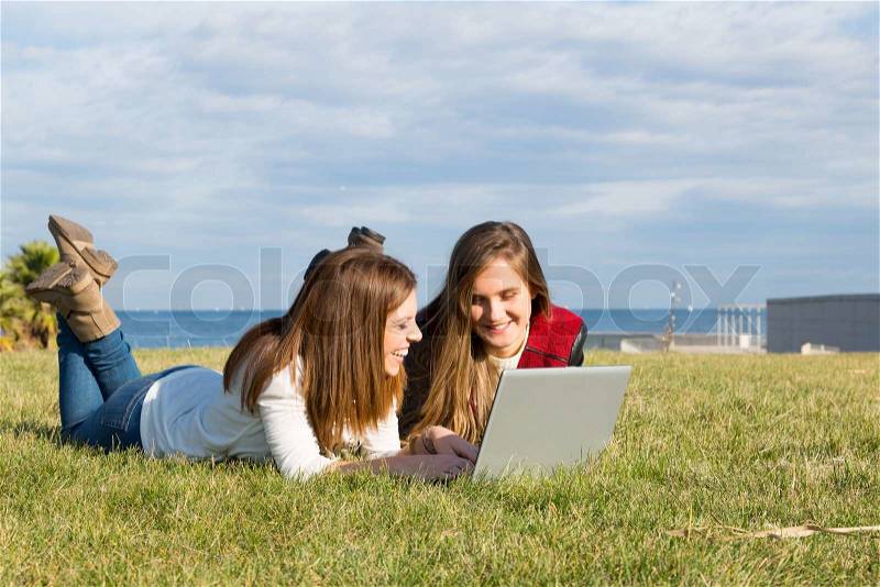 Girls in a park with a laptop at information, stock photo