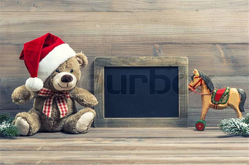 Nostalgic christmas decoration with antique toys teddy bear and wooden rocking horse. vintage style picture with blackboard for your text, stock photo
