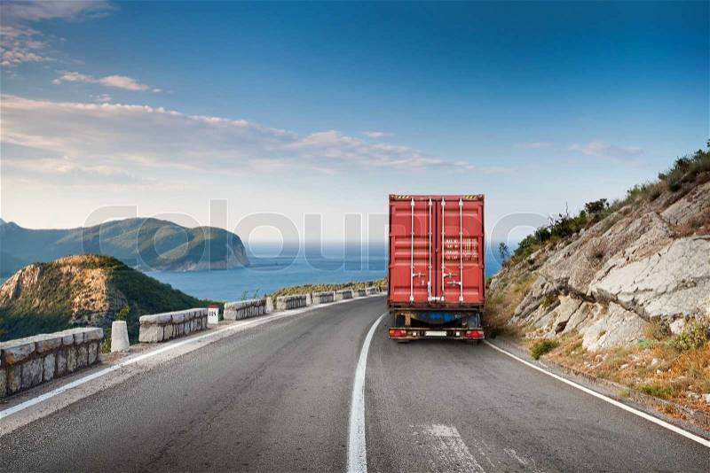 Cargo truck on the mountain highway with blue sky and sea on a background, stock photo