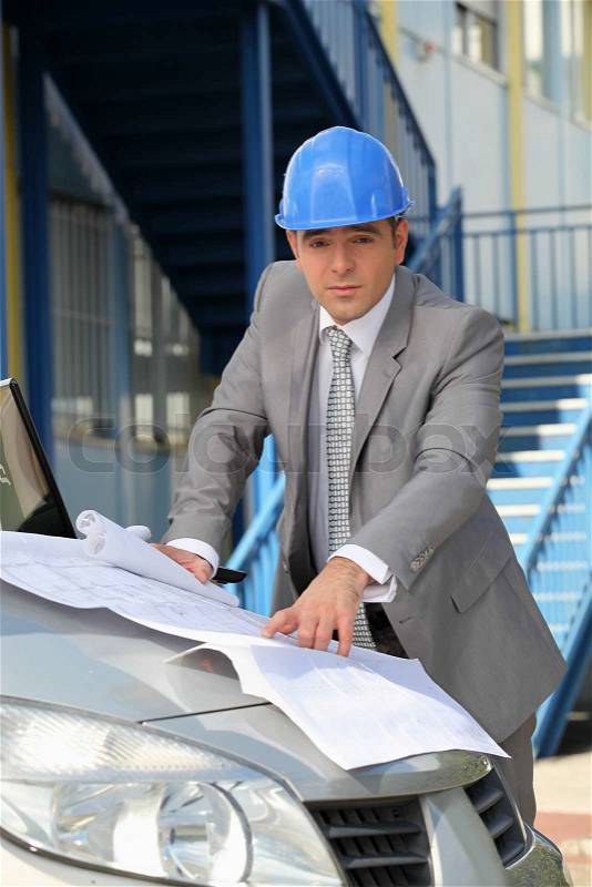 Architect looking at plans on a car bonnet, stock photo