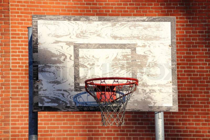 Old and worn outdoor basketball net with red brick background, stock photo