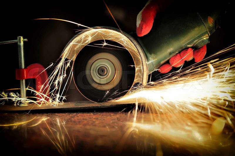 Worker cutting metal with grinder. Sparks while grinding iron, stock photo