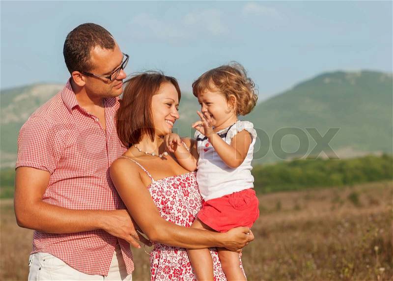 Happy mother, father and daughter in the mountains at sunset, stock photo