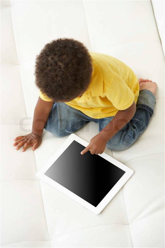 Overhead View Of Boy On Sofa Playing With Digital Tablet, stock photo