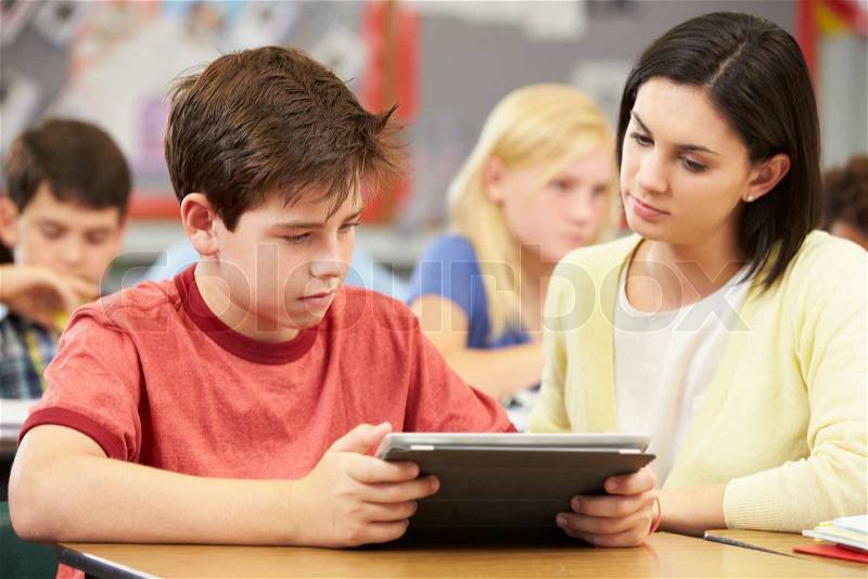 Pupils In Class Using Digital Tablet With Teacher, stock photo