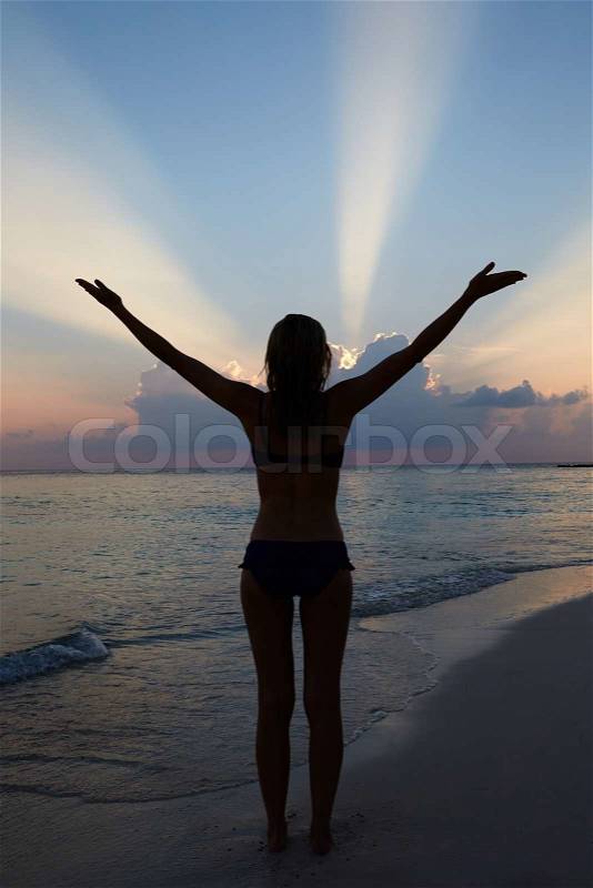 Silhouette Of Woman With Outstretched Arms On Beach, stock photo