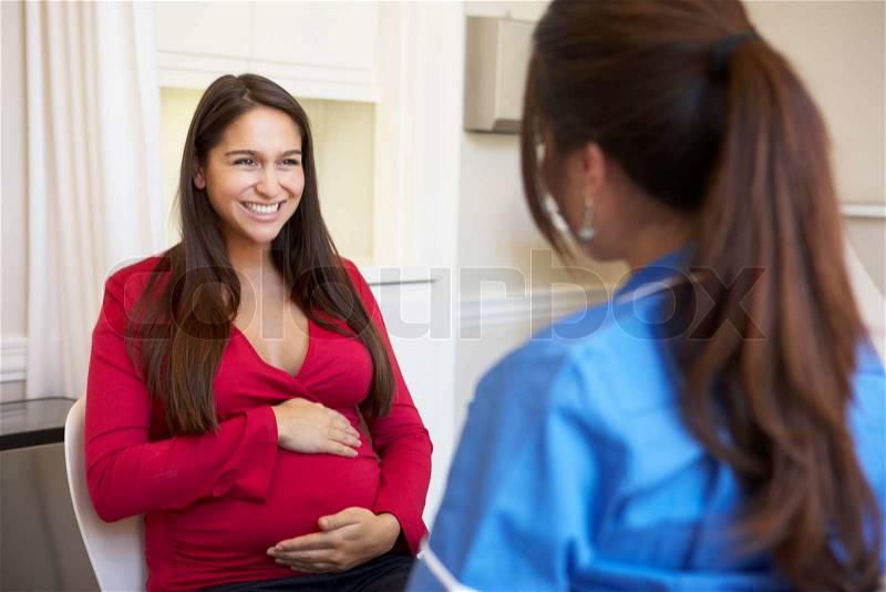 Pregnant Woman Meeting With Nurse In Clinic, stock photo