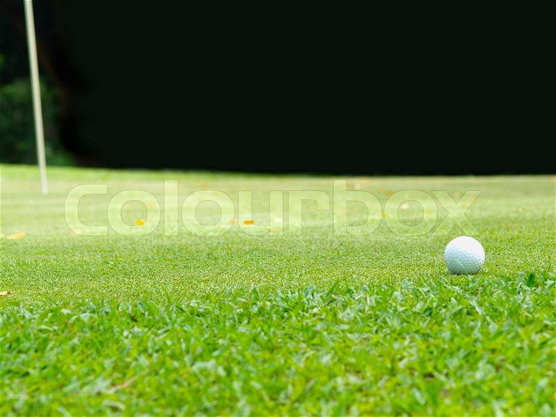 Old golf ball on green tee , stock photo